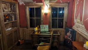 An old, rundown victorian manor with an assortment of pictures, and items laying on and around a desk.