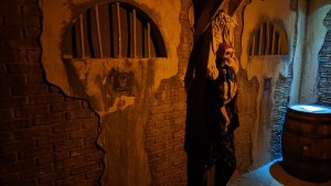 A dungeon with a pirate skeleton hung against it.