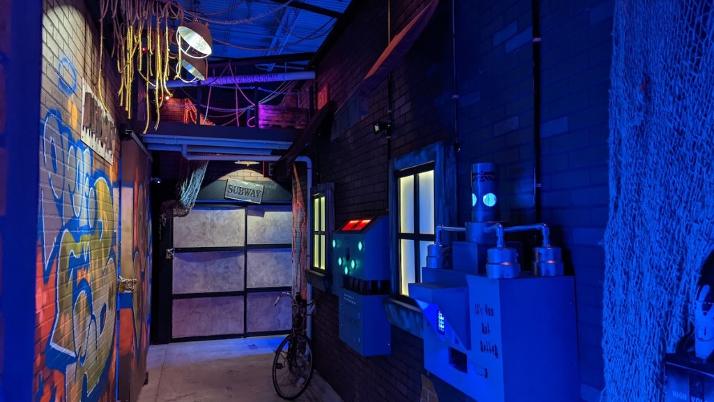 A factory-like building with brick walls, storage crates, and unusual machines.