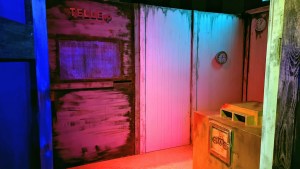 An old, run down room it looks like it might have been a back, a window is labeled, "Teller" with the "r" falling off.