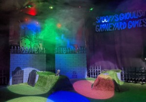 Spoopy's Ghoulish Graveyard Games set lit with spotlights and hazy with fog.