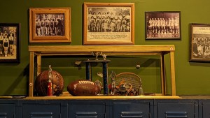 A trophy case in an old high school. There are team photos hung behind it.