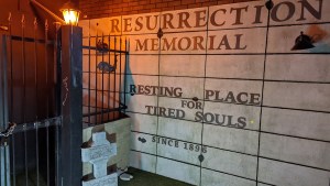A cemetery wall with the words, "Resurrection Memorial. Resting place for tired souls. Since 1896."