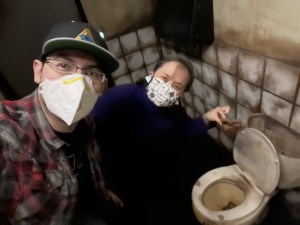 David & Tammy smiling for the camera while holding a turd over a toilet in an escape room.