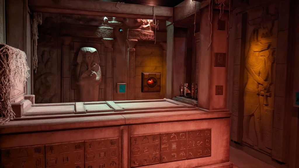 An Egyptian tomb with wall art of Anubis, and a sarcophagus.