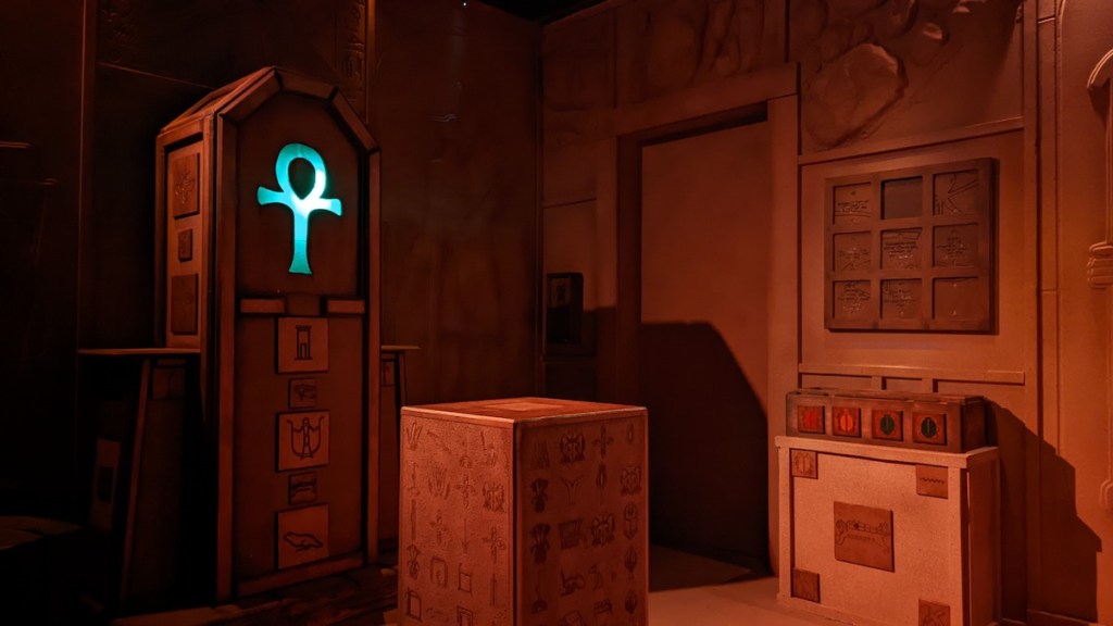 An Egyptian tomb with a sarcophagus bearing a glowing blue ankh.