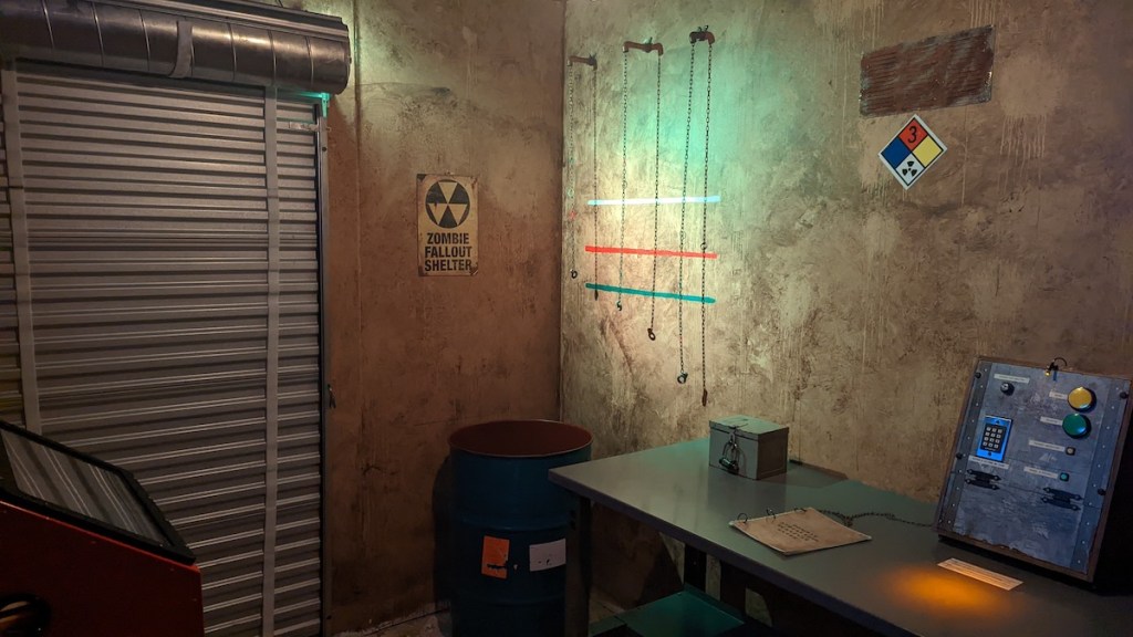 Interior of a fallout shelter with a zombie warning sign, assorted technology, locked boxes, and puzzles.