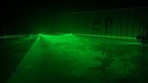A room filled with green glowing haze. Spray painted on the wall are the words, "Keep Out."