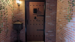 An exterior door on a brick structure. The door looks heavy, made from wood.