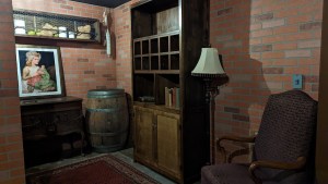 Brick walled room filled with furniture, and a barrel.