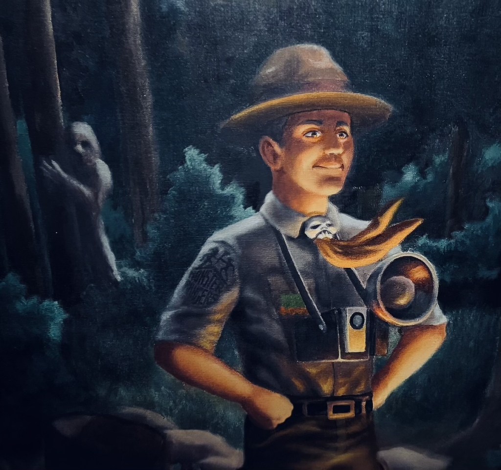 Painting of a Monster Ranger in uniform with a camera, behind him is a monster lurking in the woods.