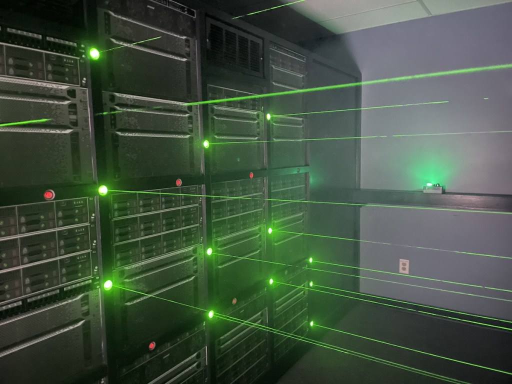 Server racks producing a laser maze of green beams.