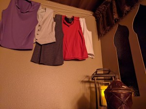 Assorted clothes on a clothing line beside a pair of windows.
