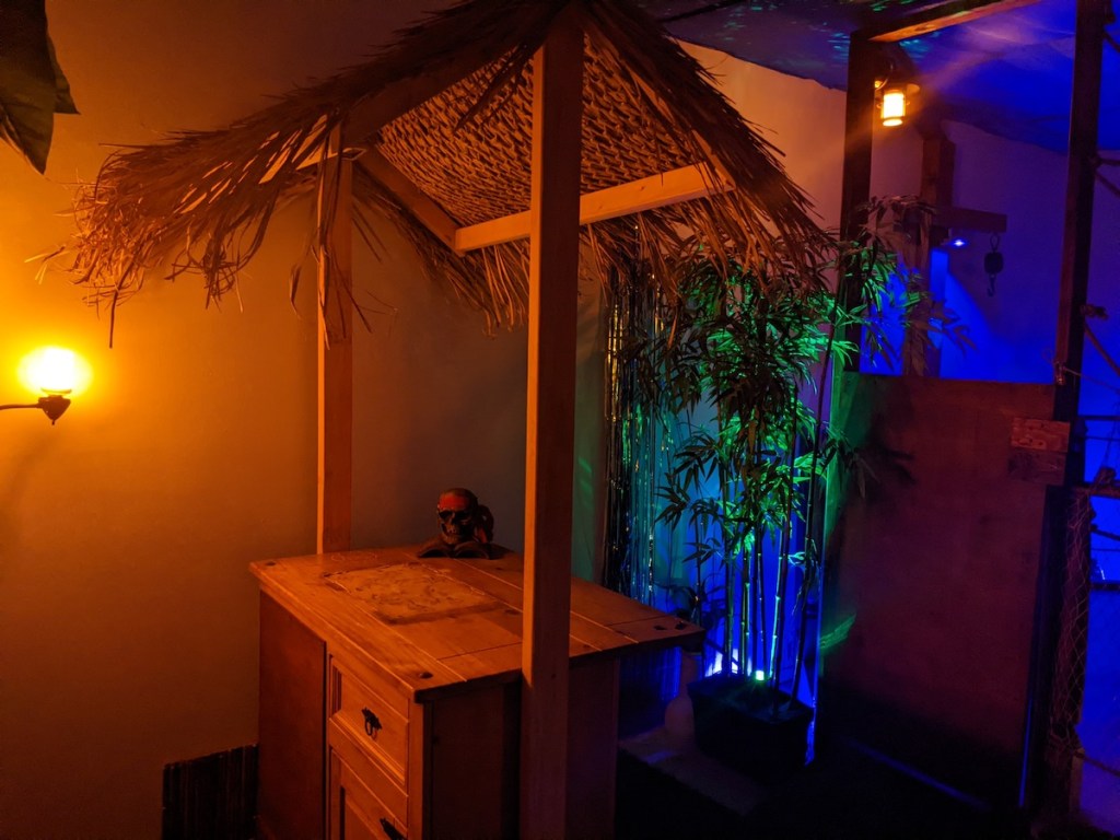 A well-like table with a thatched roof beside some tropical plants.