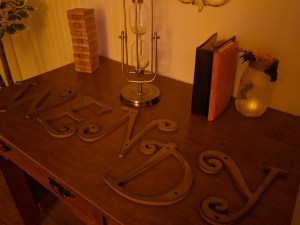 A table with wooden letters spelling "WENDY," beside a couple of books, an hourglass, and a tower of Jenga blocks.