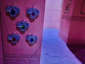 5 amulets, each with a different colored gem mounted to a pillar.