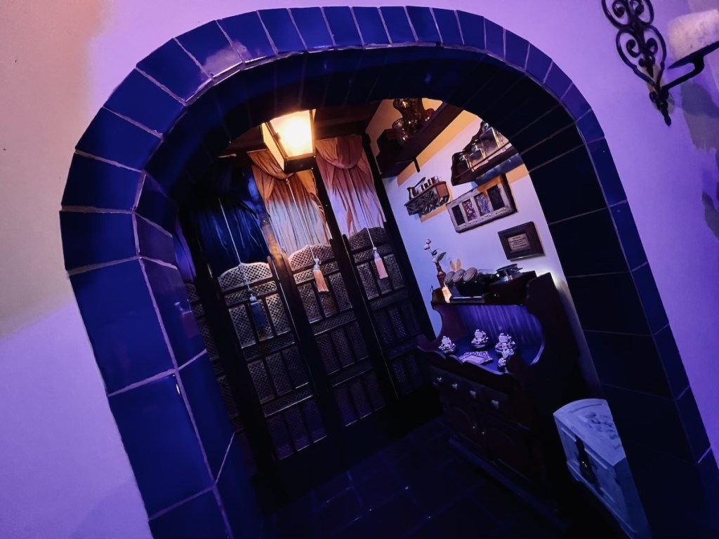 A tile archway in a market, beyond is a display and large curtains with tassels.