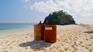 2 rusted metal barrels on a beach