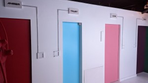 A series of colored doors in a white room. Each is labeled with an emotion such as trust, love, or anger.