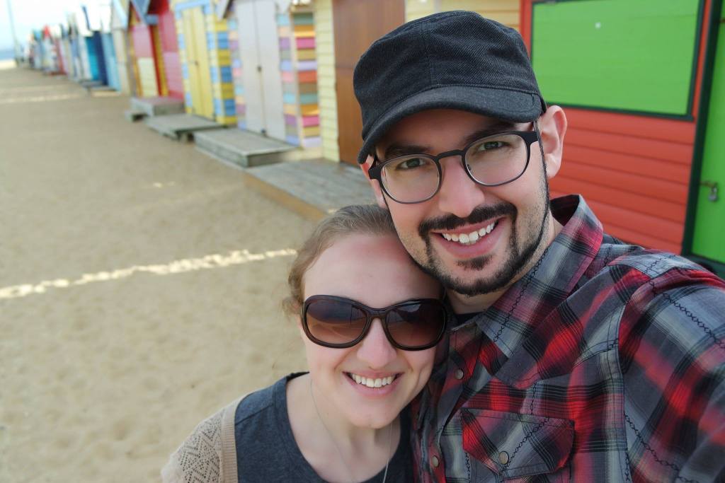 man in black cap, glasses and goatee smiling, with a blond woman smiling, wearing sunglasses and hair pulled back.