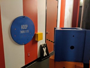 Closeup of some unusual items, a large blue disk has colored numbers on it and the words, "Hoop there it is!"