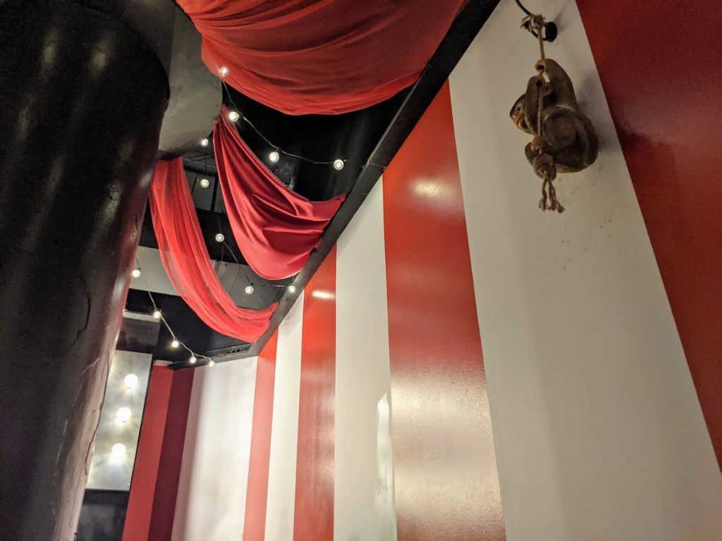 A red and white stripped wall, with a small monkey hanging from it.