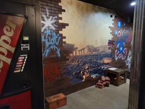 A soda machine beside a post apocalyptic hellscape.