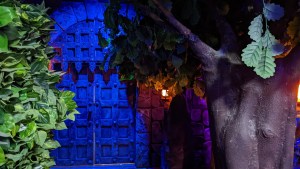 A portcullis in a castle wall beside a tree.