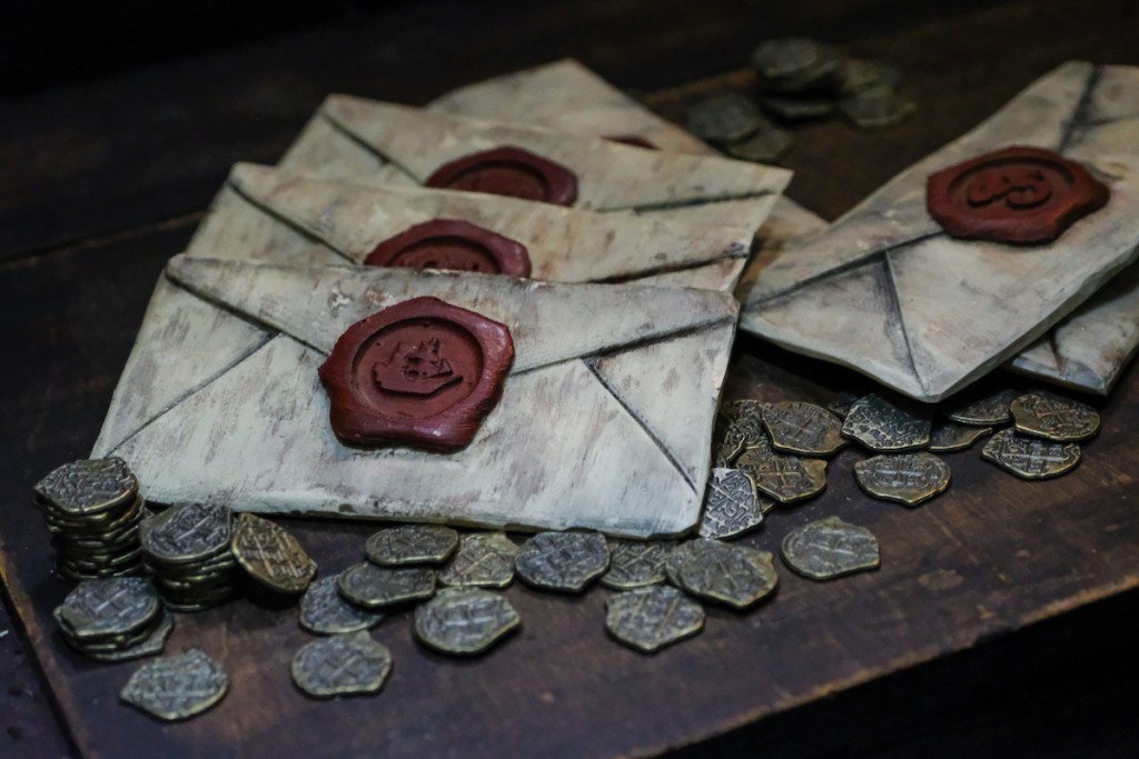 An assortment of envelopes sealed with wax, atop pirate treasure.