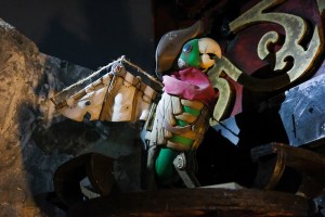 An adorable parrot in a tri-corner hat, with an artificial win made of wood, rope, and cloth.