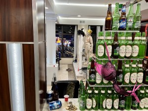 A tower of empty beer bottles with a bra hanging from it.
