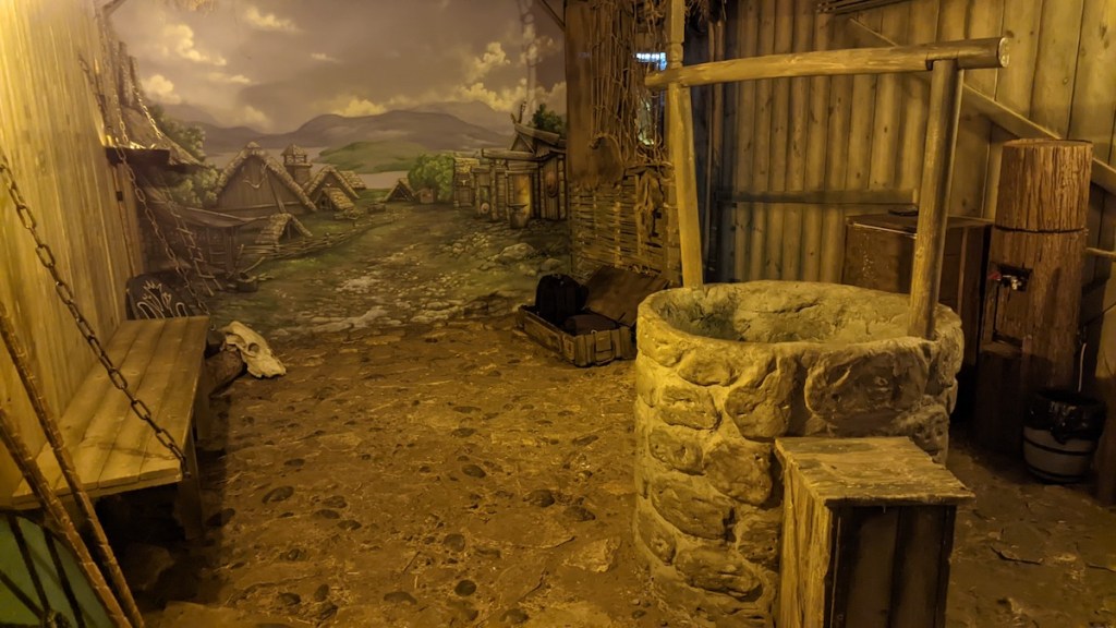 An old viking village with a well in the middle of a path.