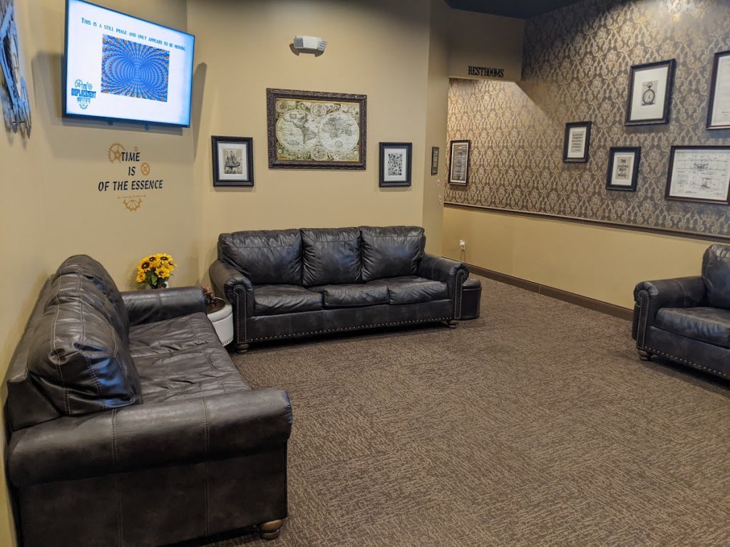 A brown escape room lobby with 3 large couches.