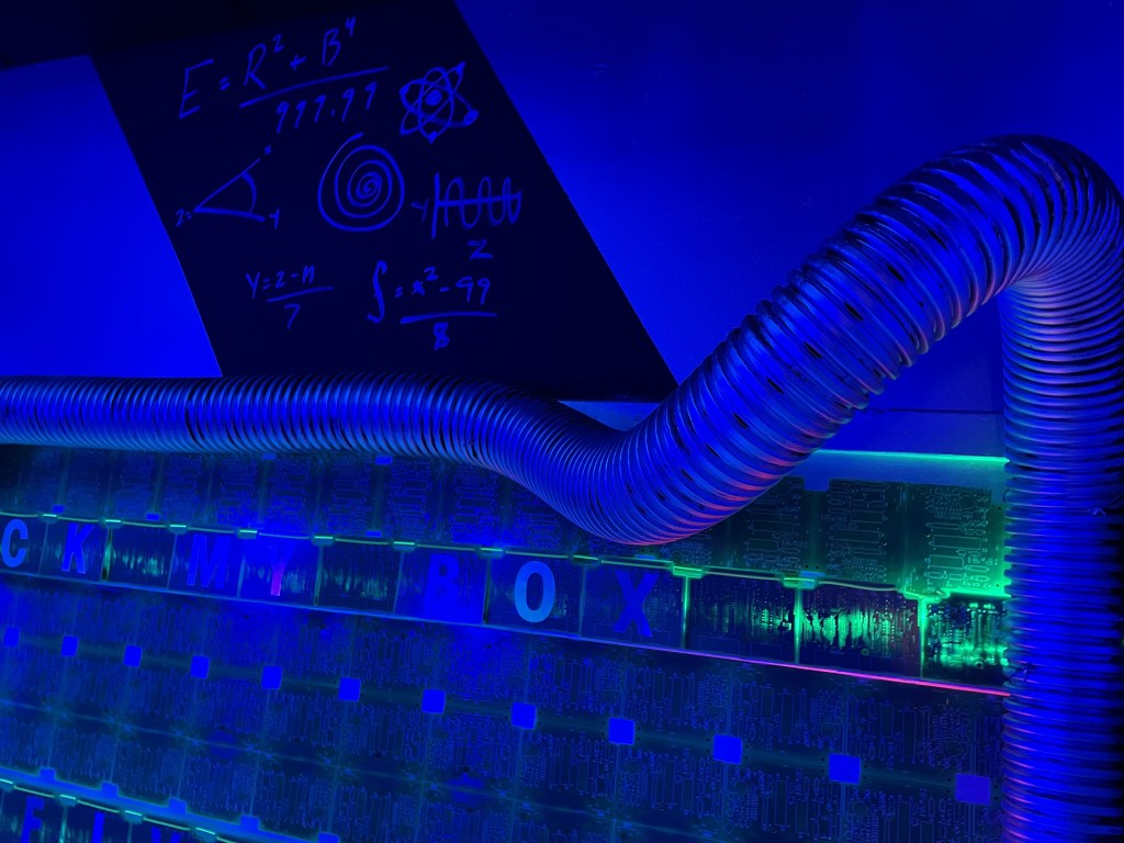 A wall of circuit boards with silver tubing, and a math equation.