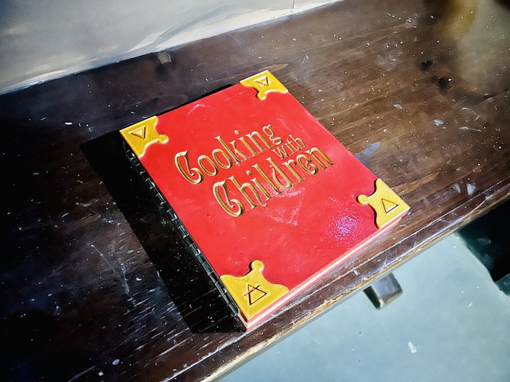 A big red book with gold writing that reads, "Cooking with Children"