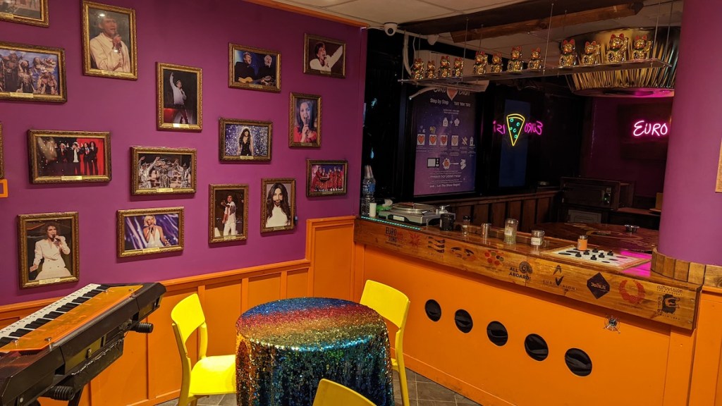 A bar with photos of singers on the wall, and a keyboard int eh corner.