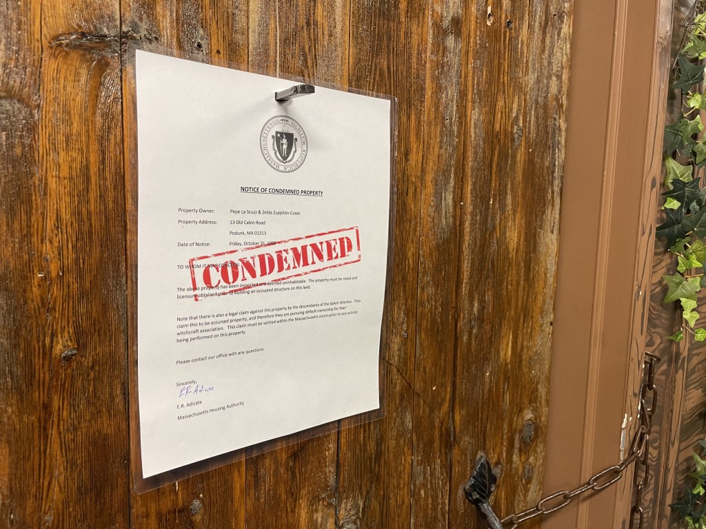 A notice of condemnation nailed to a wooden door.