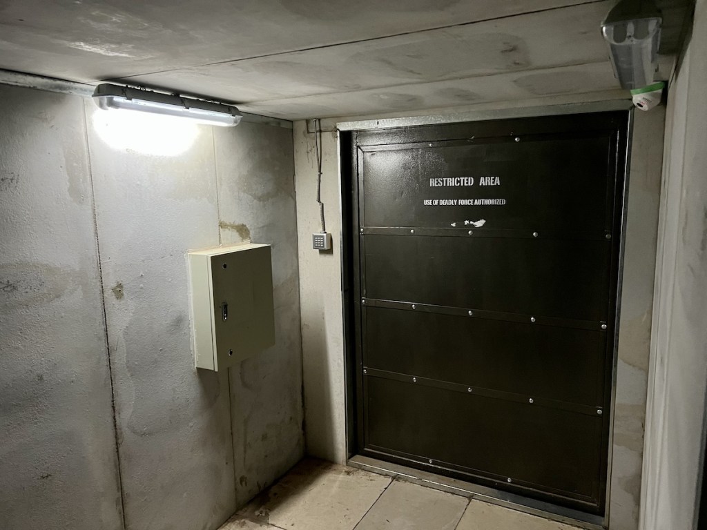 A massive metal door labeled "Restricted Area" in a concrete structure.