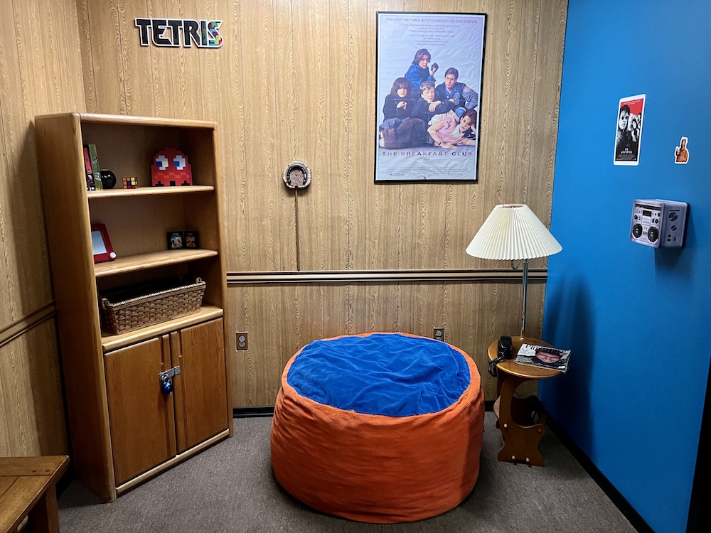 A wood paneled 80s basement with a large beanbag chair and assorted toys.