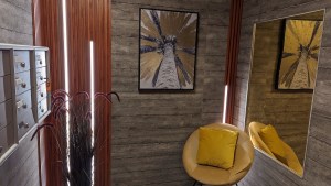 A calm space with a small seat, some art, a mirror, and apartment mailboxes.