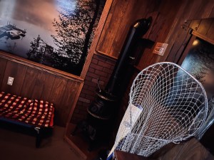 Camp cabin interior with a furnace, a sleeping bag, and a fishing net.