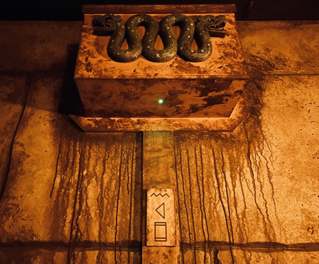 A box hung from an old stone wall with a two-headed snake.