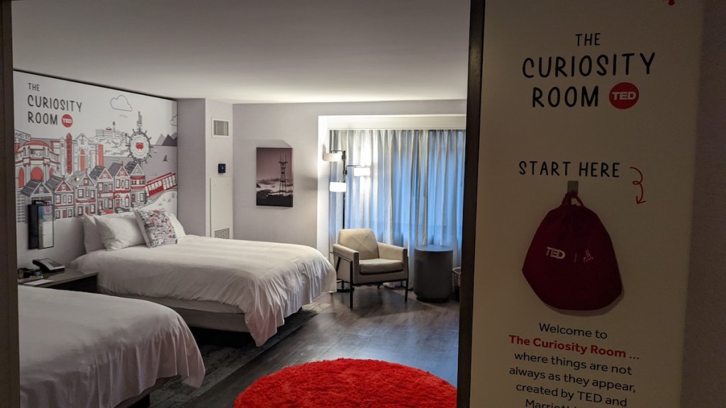 A TED themed hotel room, a sign reads, "The Curiosity Room: Start Here"
