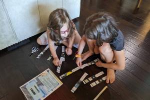 Two children solving a puzzle that they had to cut into multiple pieces with safety scissors.