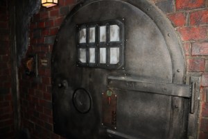 Closeup of a large metal boiler door set into a brick wall.