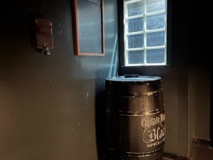 A large barrel of Captain Morgan rum beside a window in a dimly lit room.