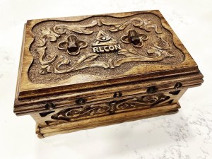 wooden puzzle box with decorative carvings, and the RECON logo carved onto the top