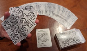 A deck of cards with an intricate maze-like design on the backs, fanned out beside their box.