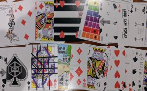 An assortment of playing cards, each with unusual added text and illustrations on their faces.