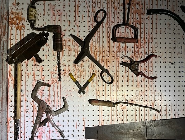 A pegboard with tools covered in blood.